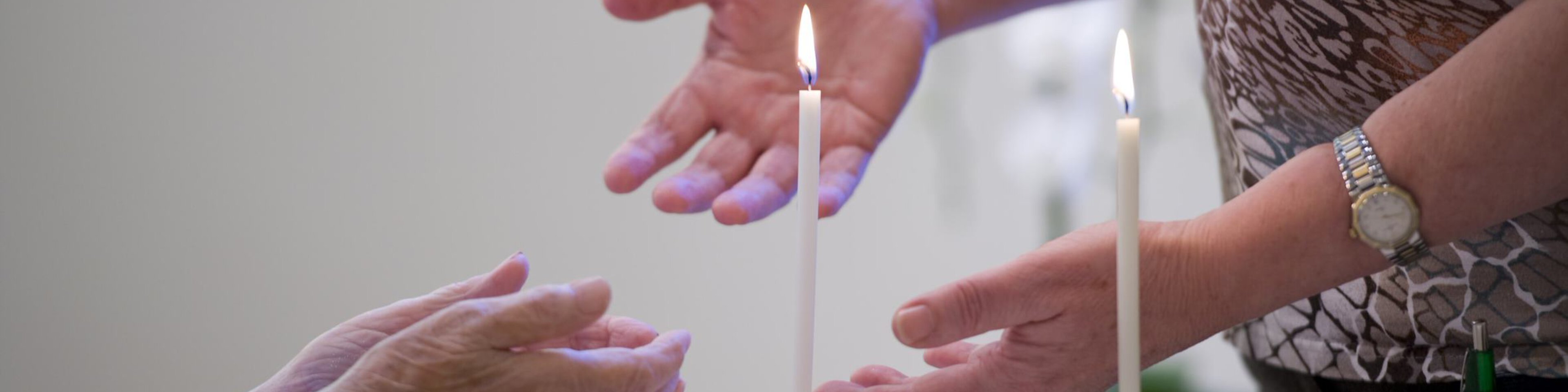 Hände von zwei Personen reichen sich in der Kirche | © Caritas München und Oberbayern