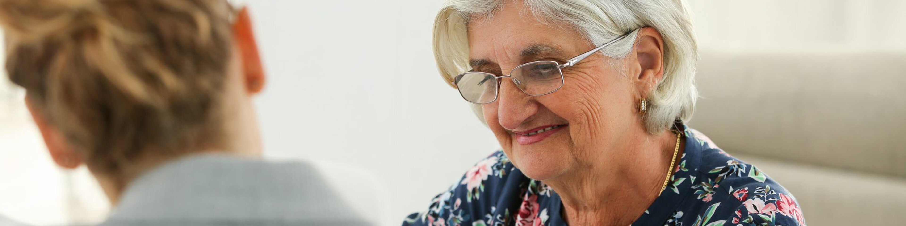 Eine Frau berät eine lächelnde ältere Frau | © Caritas München und Oberbayern
