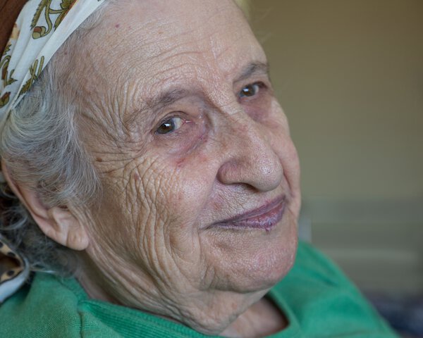 Eine ältere Frau mit Tuch auf den Kopf lacht in die Kamera | © bernanamoglu - stock.adobe.com