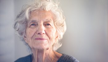Eine ältere Frau lächelt in die Kamera | © ivanastar - GettyImages